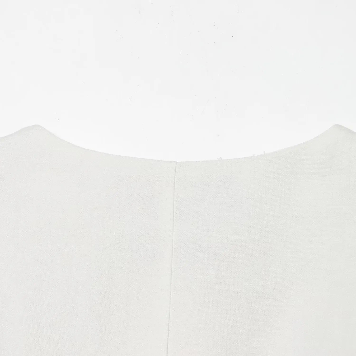 Close-up of the round neckline and center back seam on the off-white structured dress