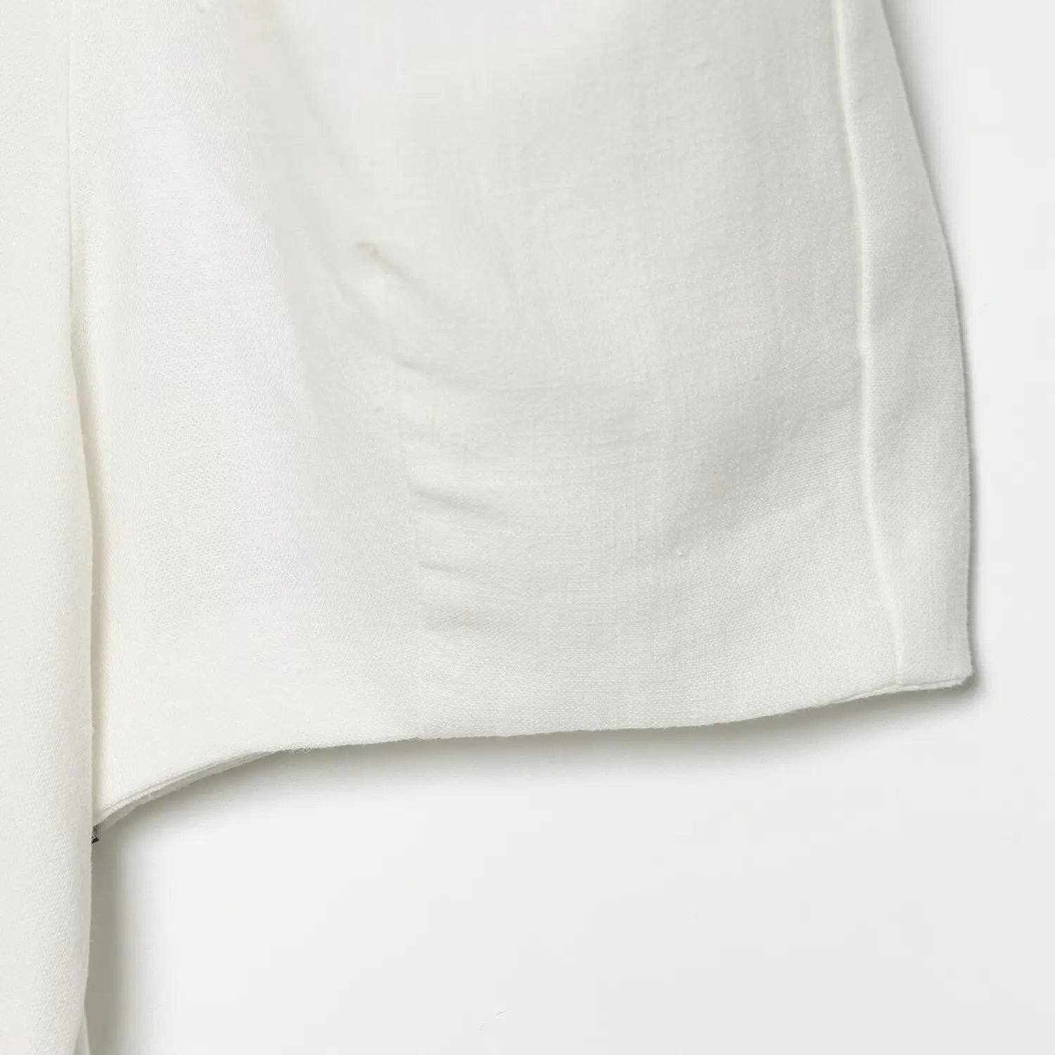 Close-up of the side seam stitching and hemline on the off-white crepe dress