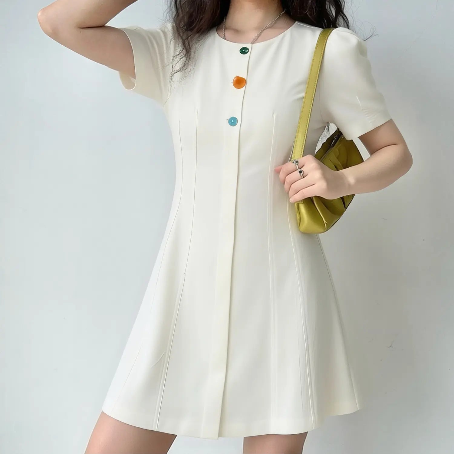 Lifestyle shot of model wearing the off-white puff sleeve dress, showing the A-line silhouette and colorful buttons