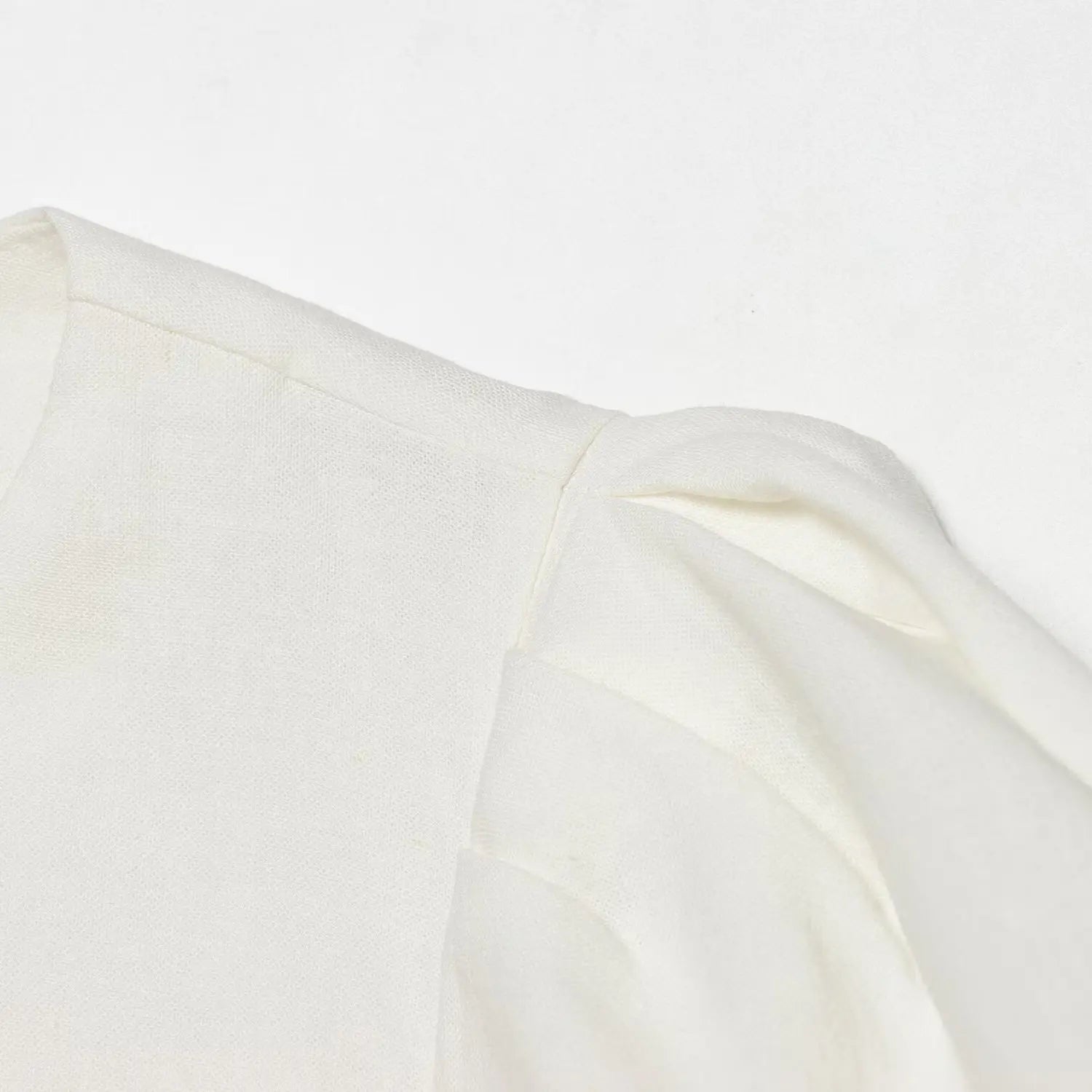 Close-up of the shoulder seam and puff sleeve construction on the off-white dress
