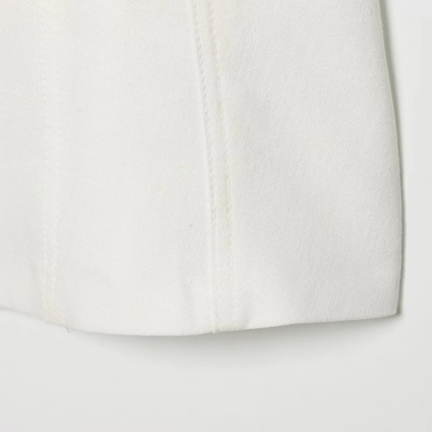 Close-up of the side seams and finished hem on the off-white structured dress