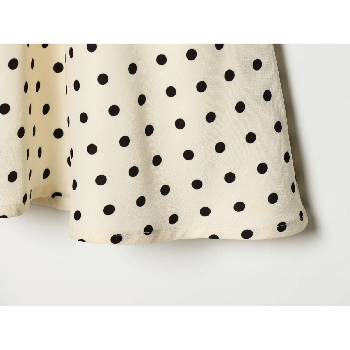 Off‑white black polka dot dress skirt hem stitching close‑up,neat finished hem