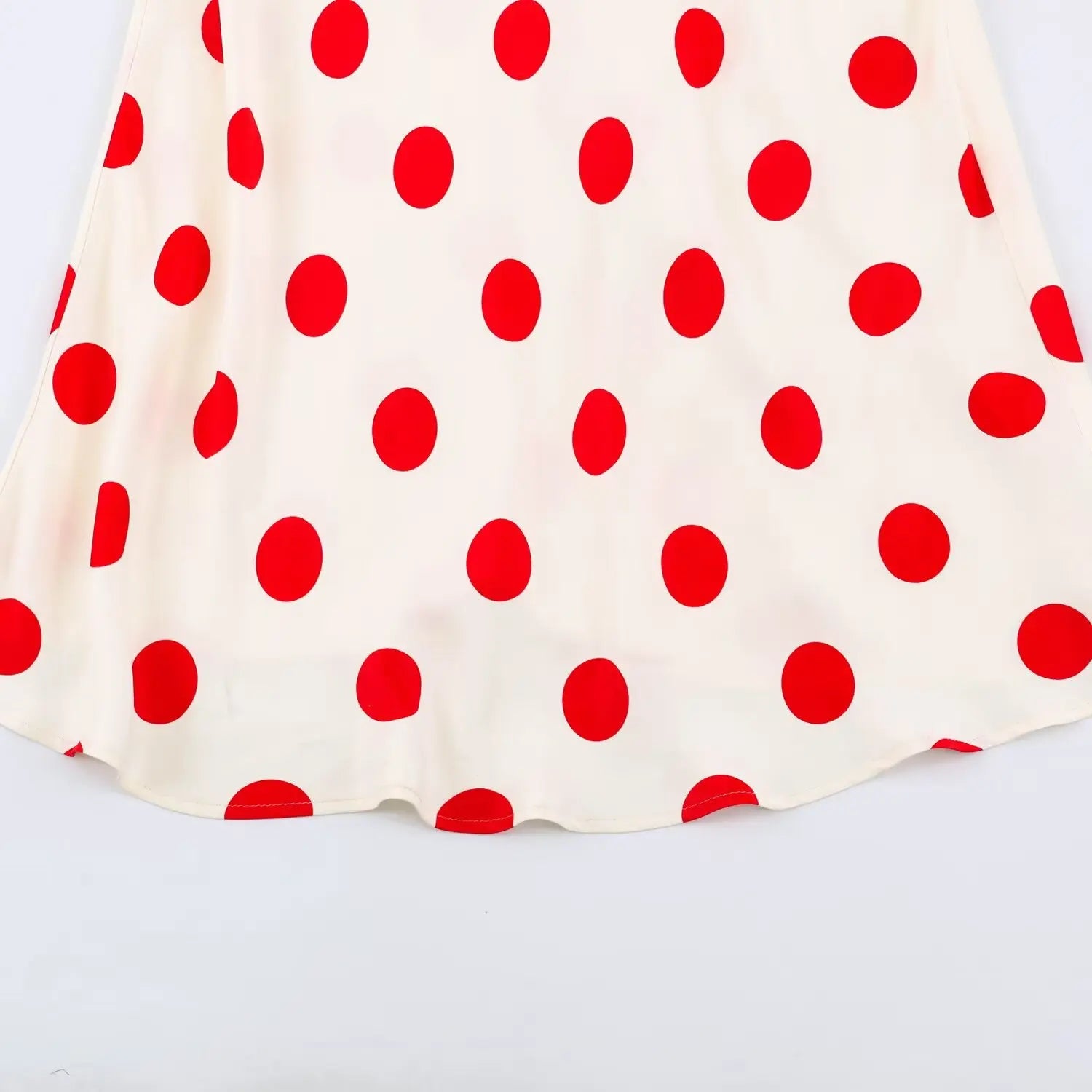 Close‑up of flared hem on off‑white red polka dot maxi dress