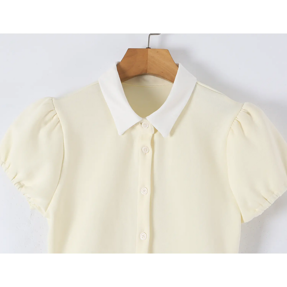 Close-up detail of offwhite dress white contrast collar, puff short sleeve and front button placket