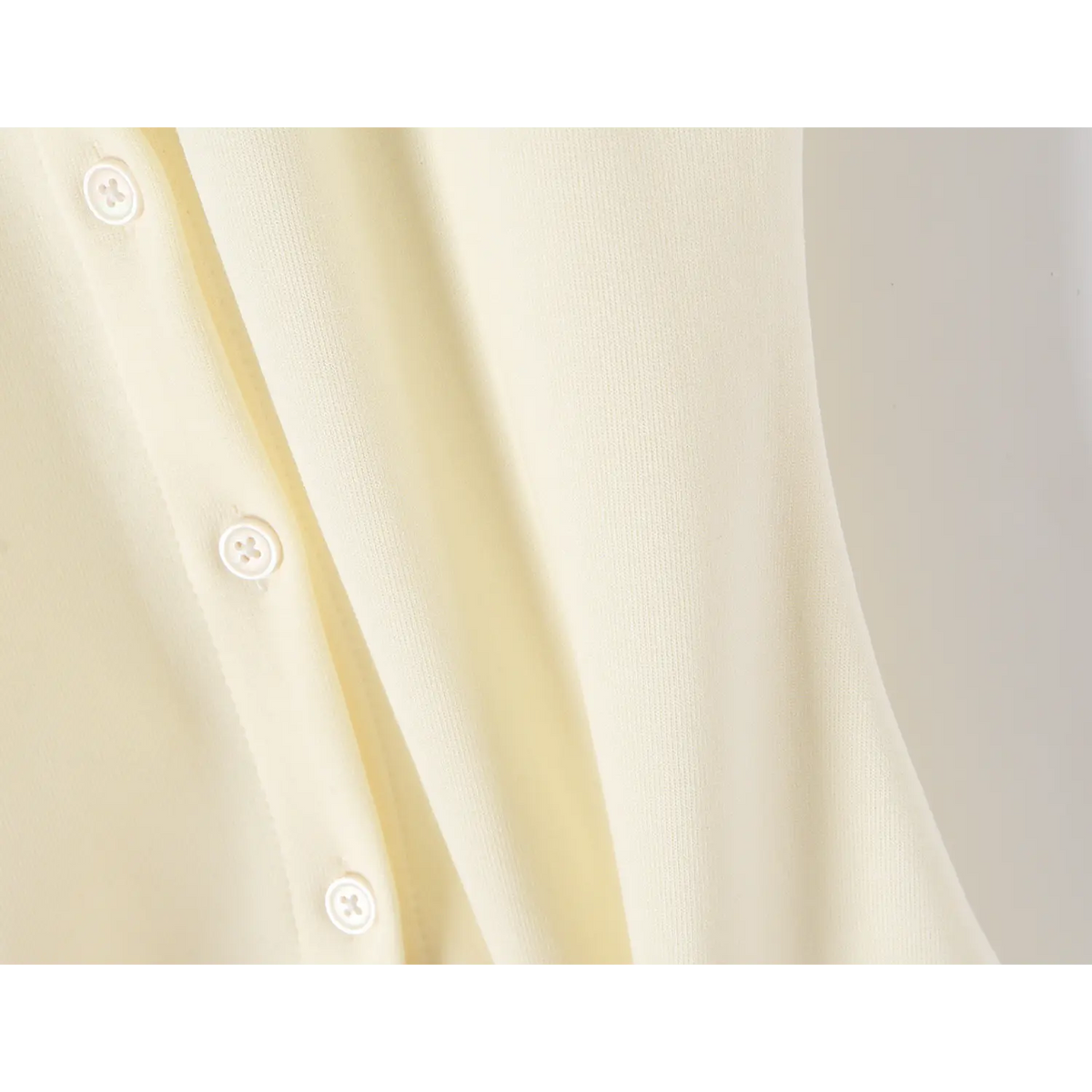 Close-up of offwhite dress fabric drape, front round buttons and soft stretch material