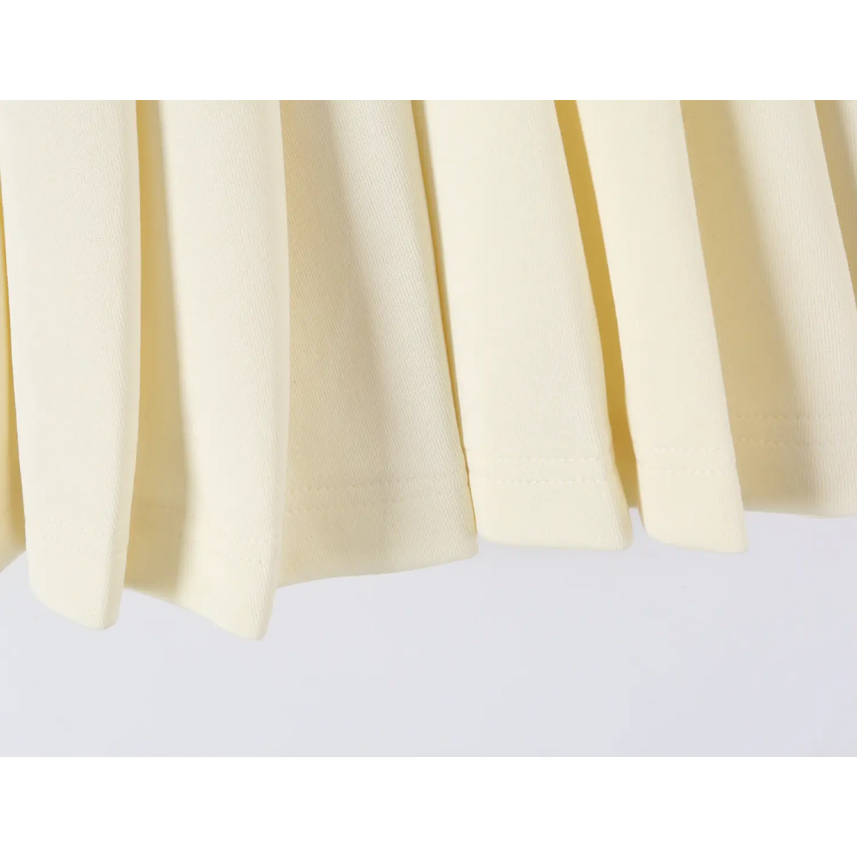 Extreme closeup of offwhite dress skirt hem, fine fabric texture and neat finished stitching