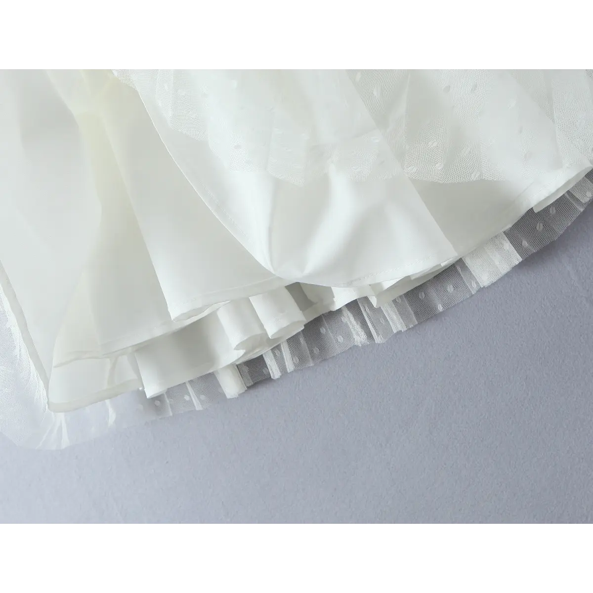 Close-up detail shot of cream coquette dress, scalloped lace sweetheart neckline decorated with small front satin bow.