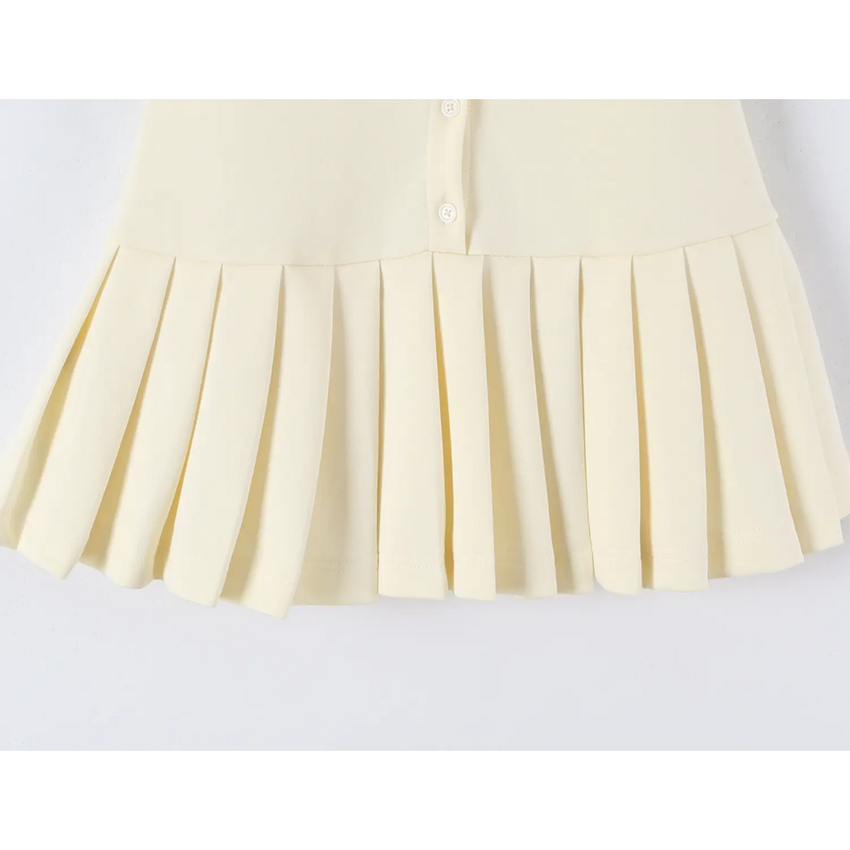 Partial shot of offwhite mini dress pleated hem, fitted waist and pleated skirt design