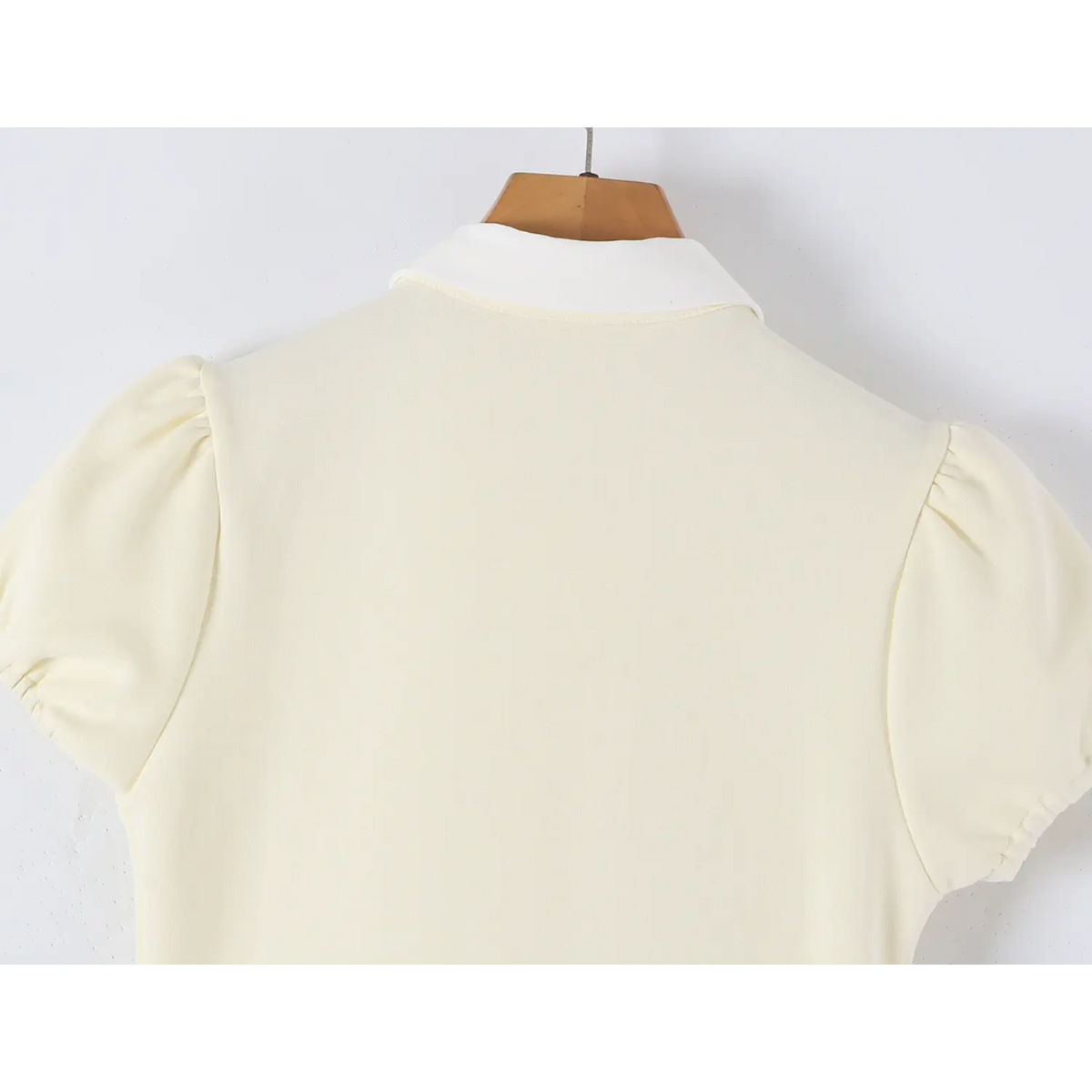 Back view detail of offwhite mini dress with white collar and puff short sleeves on hanger