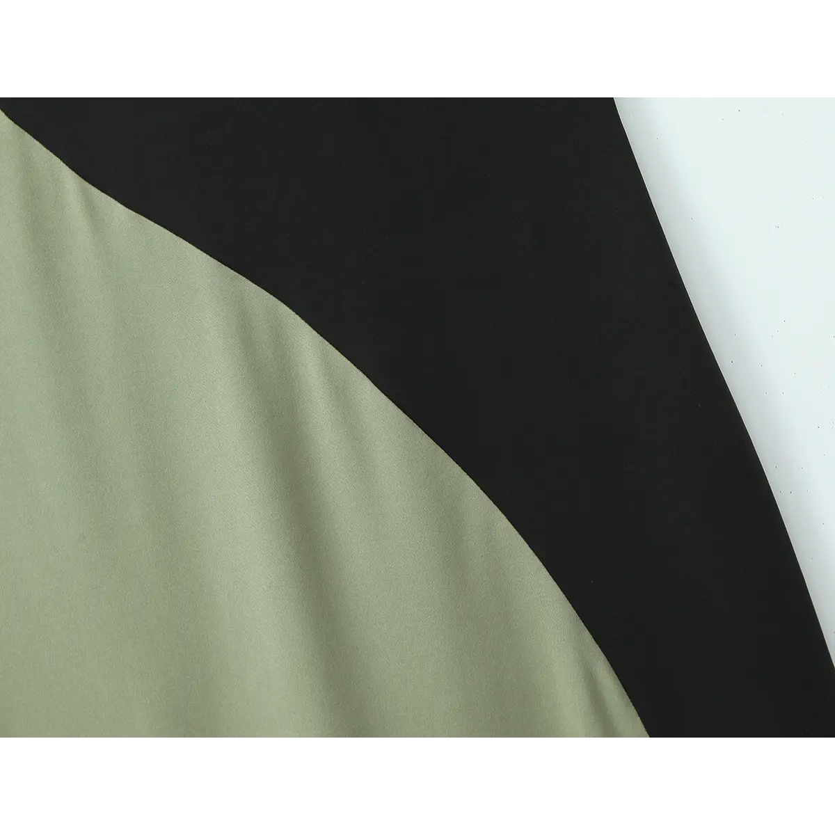 Close-up of the diagonal seam where the olive green and black color blocks meet.