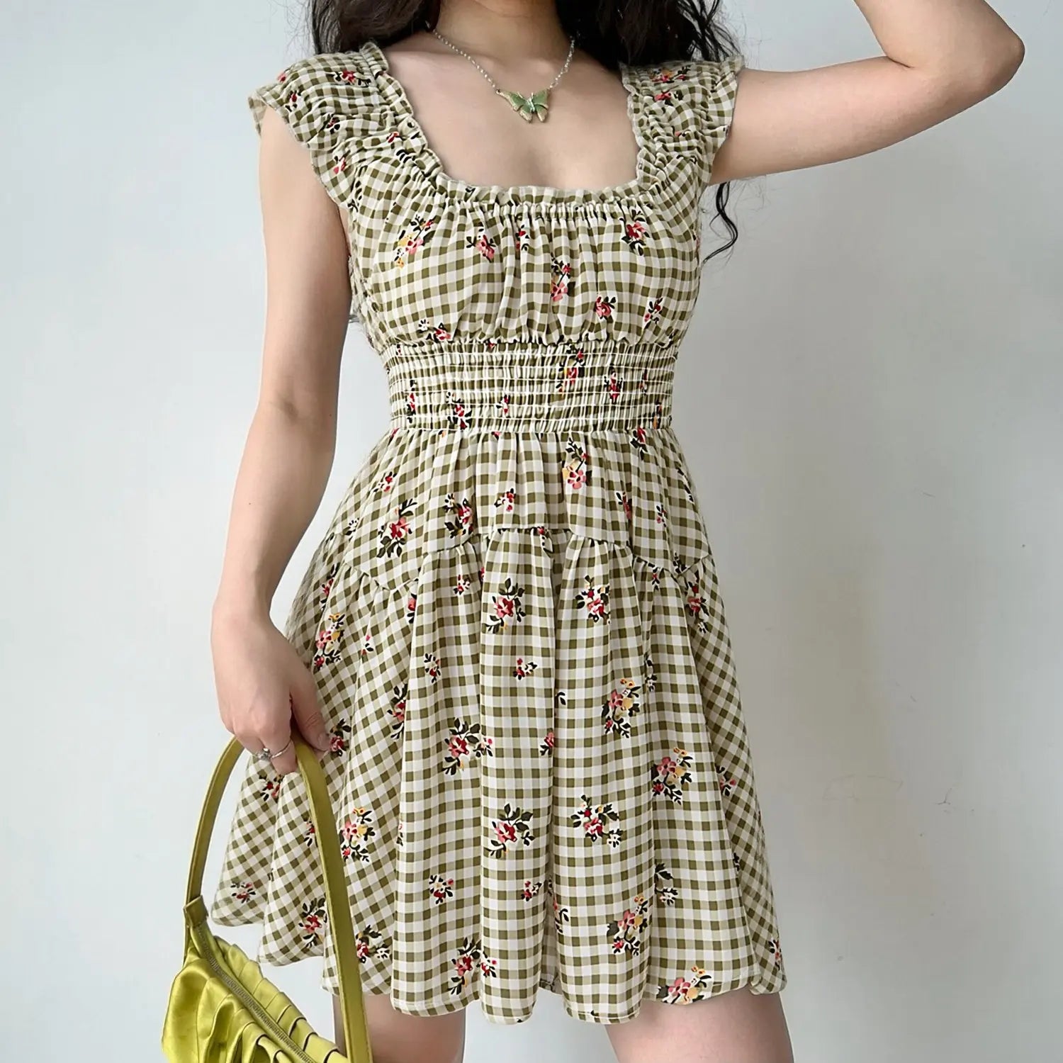 lifestyle photo woman in olive green gingham pink rose floral mini dress elastic smock waist ruffle cap sleeve casual summer dress