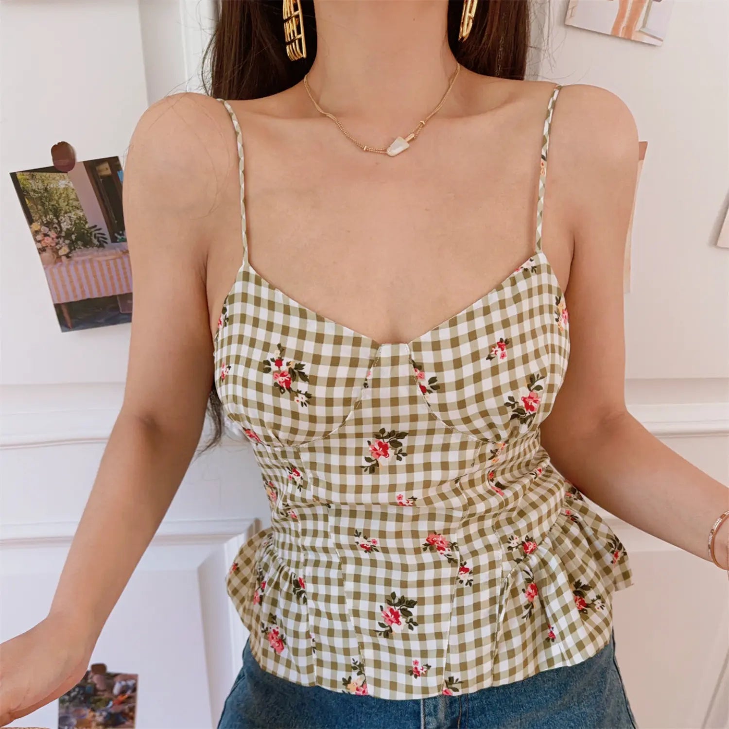 Female model wearing olive white gingham floral camisole top, sweetheart neck thin adjustable straps peplum ruffle hem paired with blue denim shorts