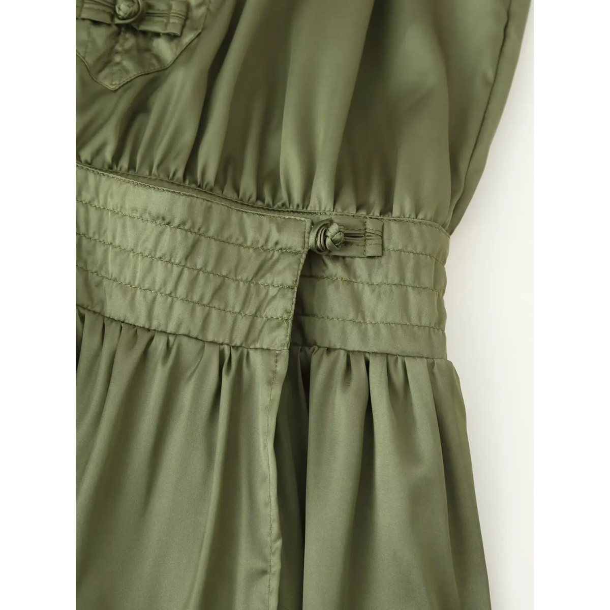 Close-up of smocked waistband and frog button