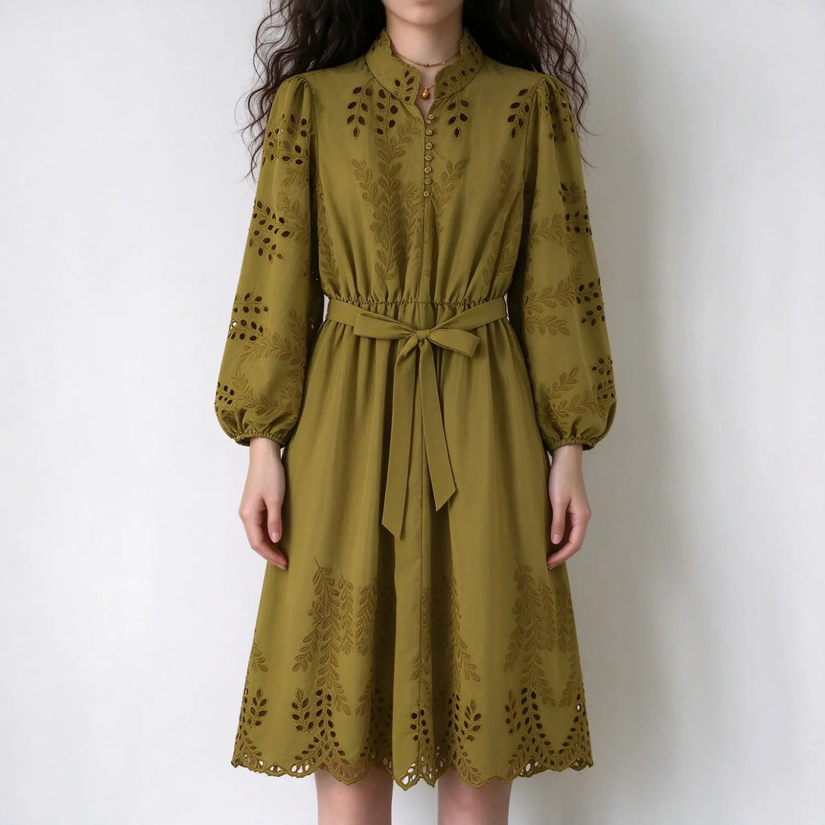 Model wearing olive green eyelet embroidered midi dress, stand collar, balloon long sleeves, waist self tie belt, scalloped hem