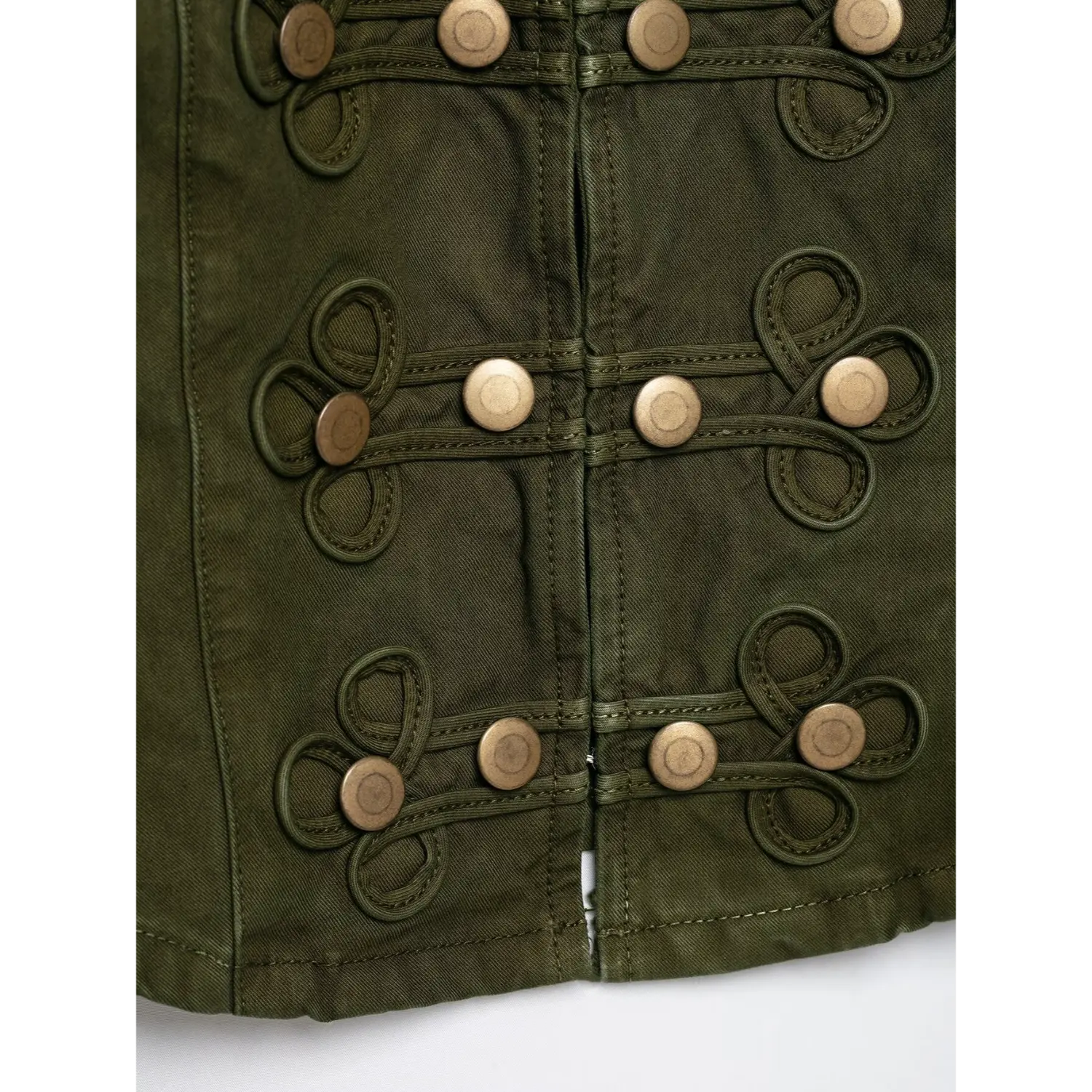Macro close‑up of front decorative knot loop trim and antique brass metal buttons, olive green washed twill textile