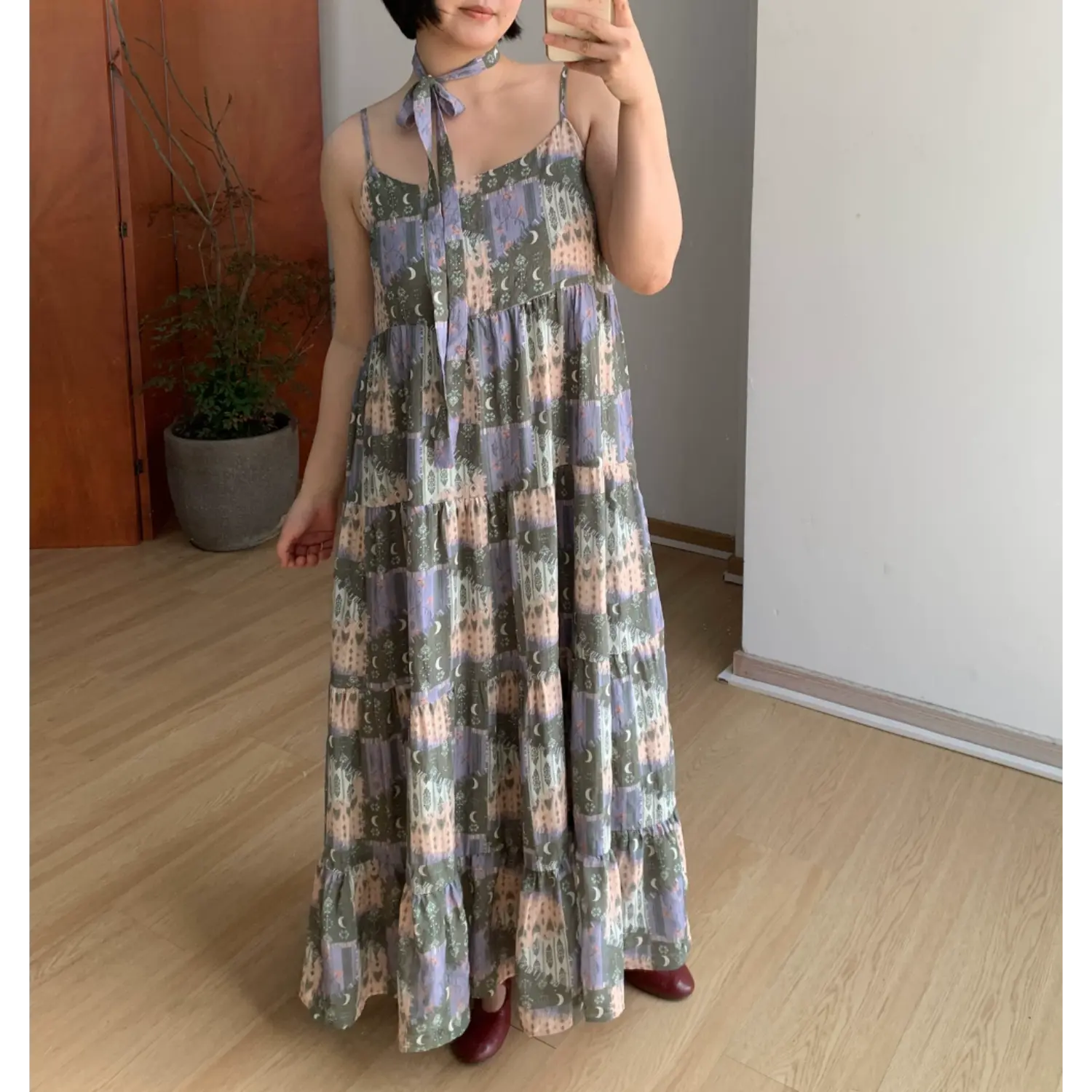 Olive green vintage moon forest print cami tiered maxi dress, thin straps matching printed neck tie, full body indoor model shot with red mary jane shoes