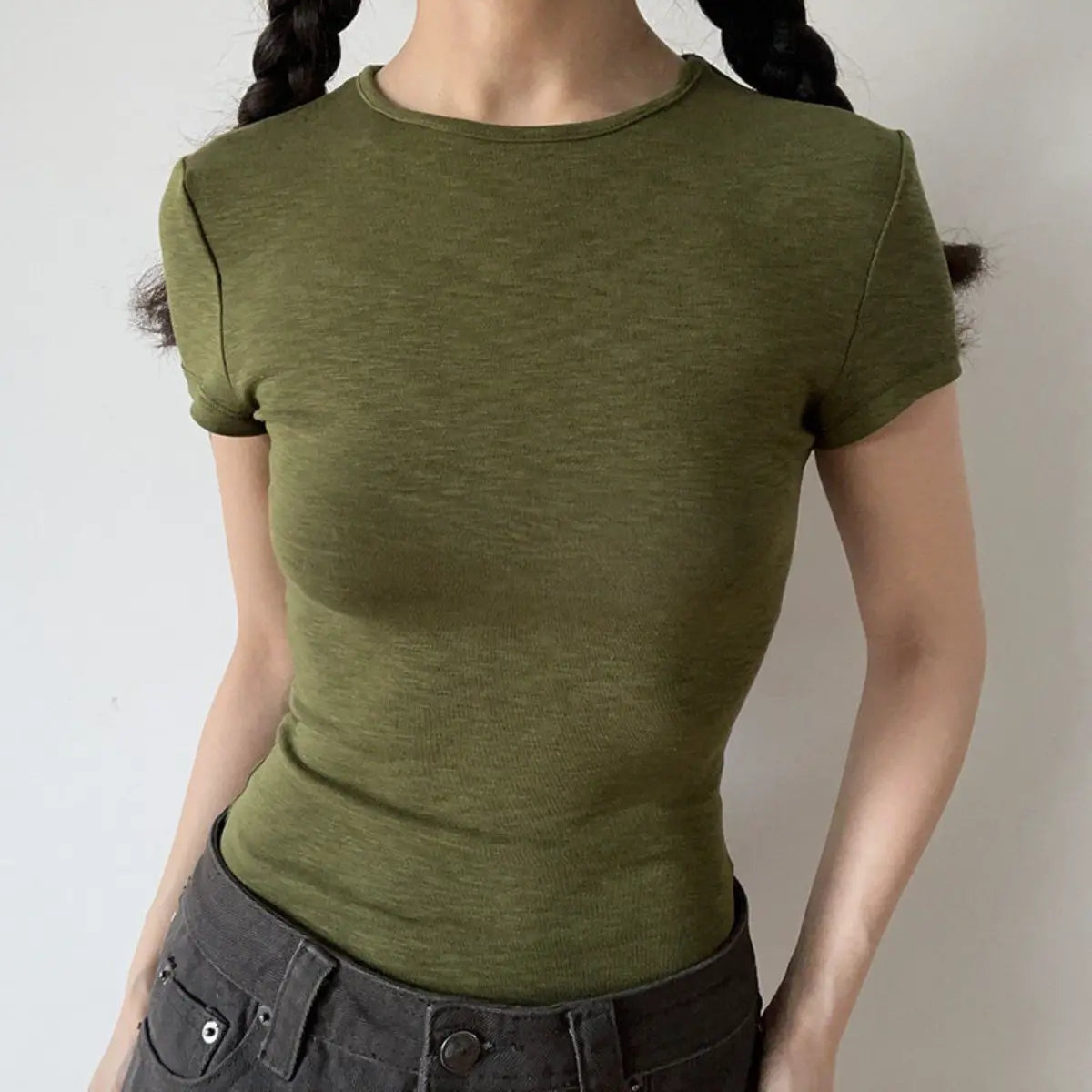 Lifestyle shot of form-fitting olive green ribbed crew-neck short-sleeve t-shirt, tucked into jeans