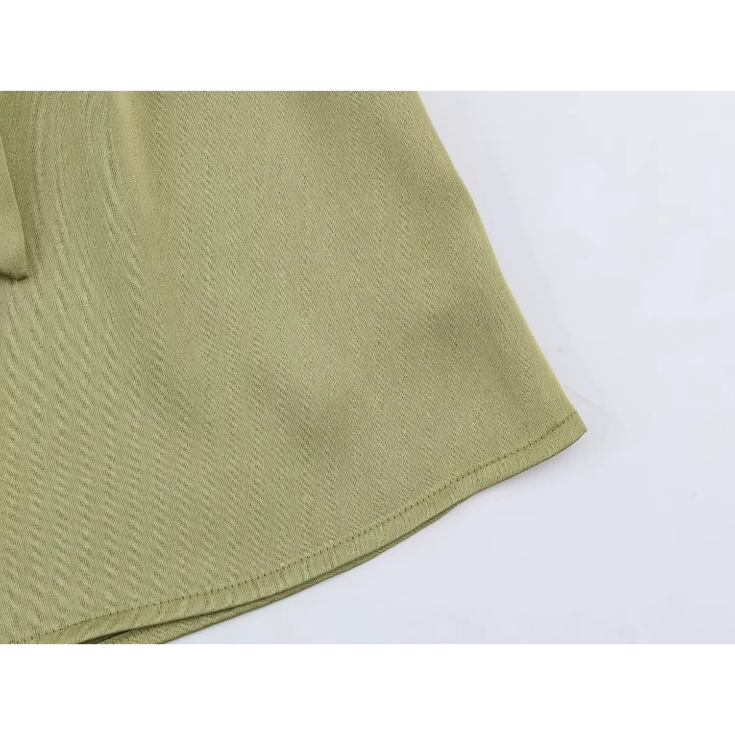 Side curved hem closeup, neat folded overlock finishing, subtle satin crease texture