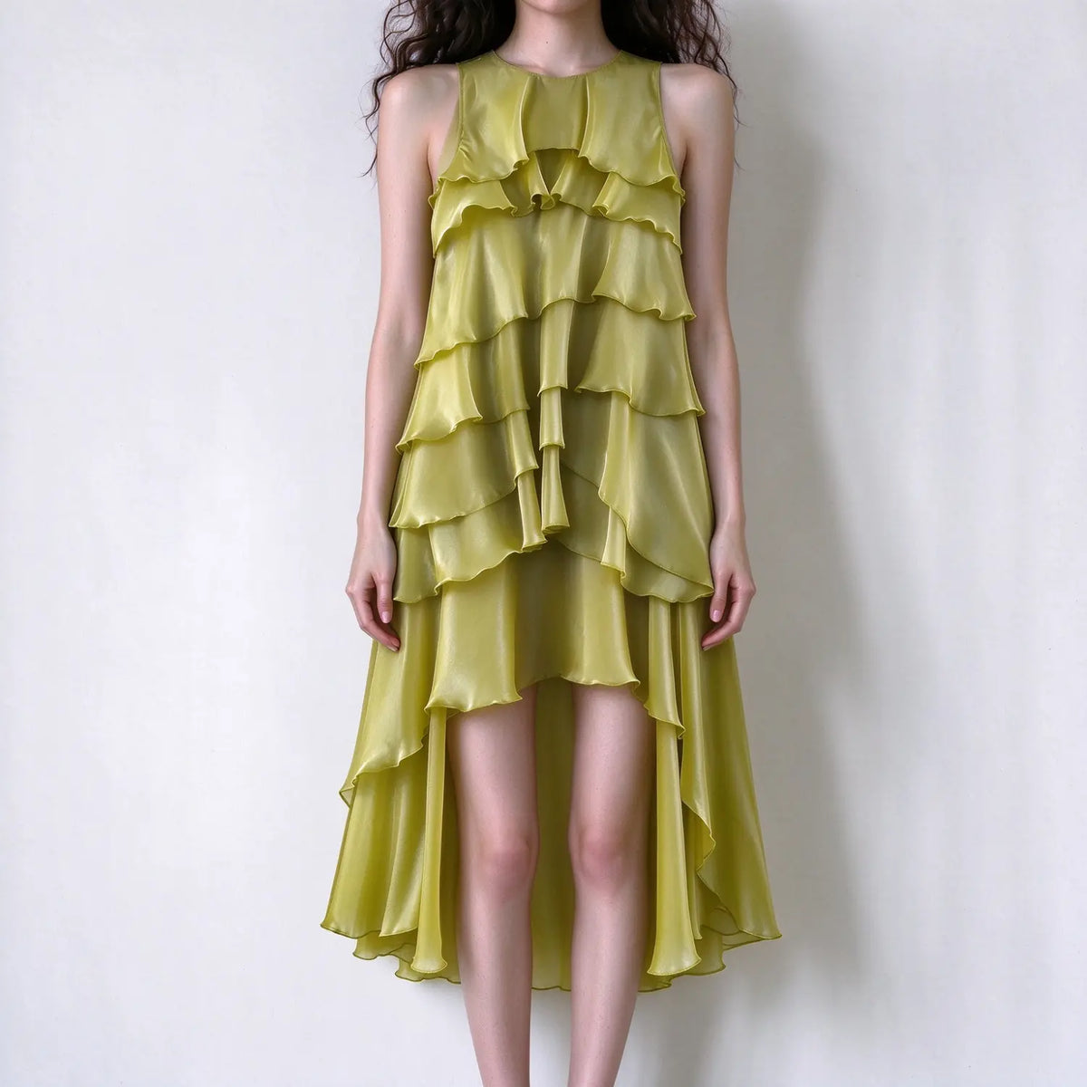 Model wearing olive green sleeveless tiered ruffle maxi dress, round neck, high low asymmetrical hem, shiny lightweight fabric, plain white background