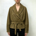 Model wearing olive suede wrap collar belted cropped jacket with black trousers