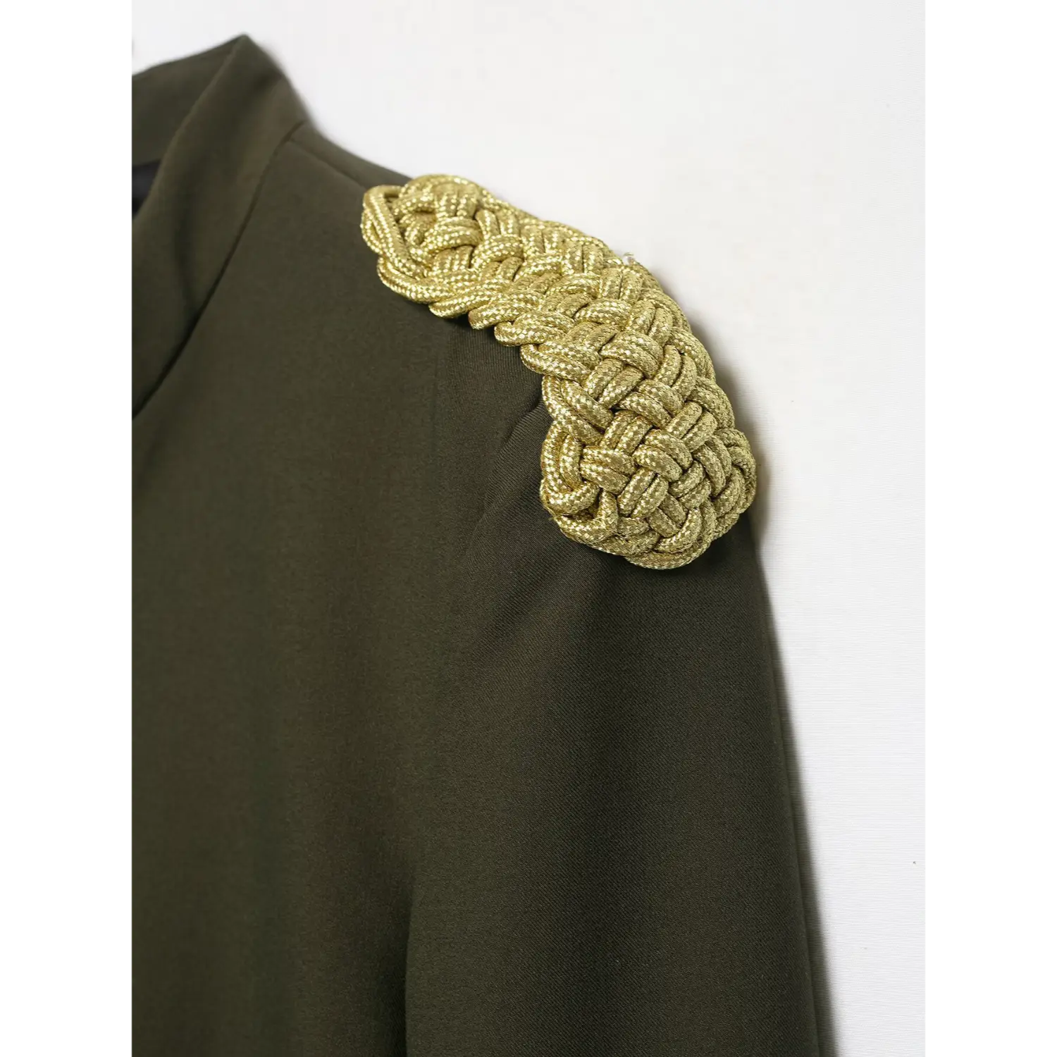 Detailed close‑up texture shot of thick gold braided shoulder epaulet on olive green cropped blazer