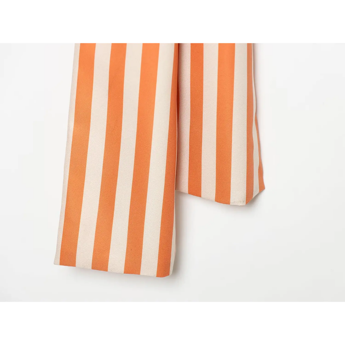 Close‑up of loose belt tails, orange and cream horizontal striped fabric, neat finished hem