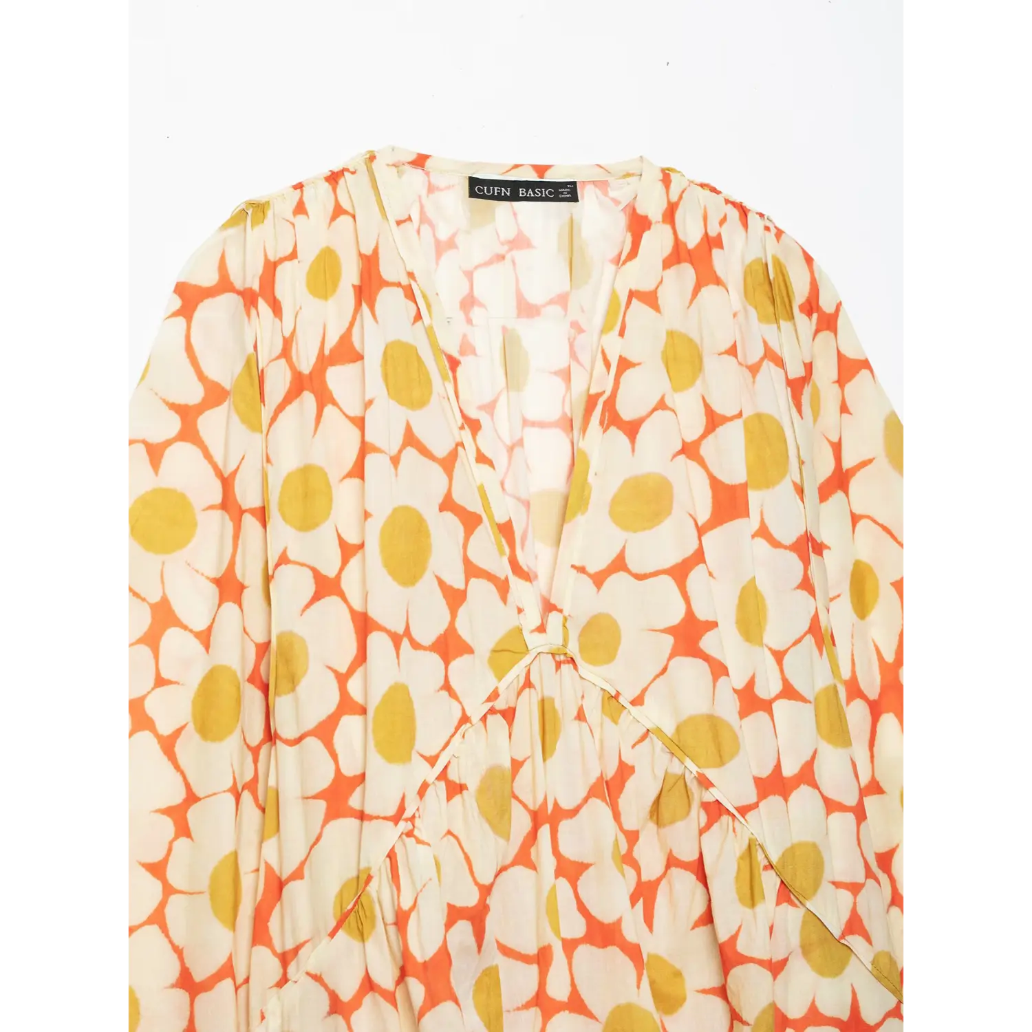Close‑up of v‑neck gathered bodice on orange daisy floral print maxi dress