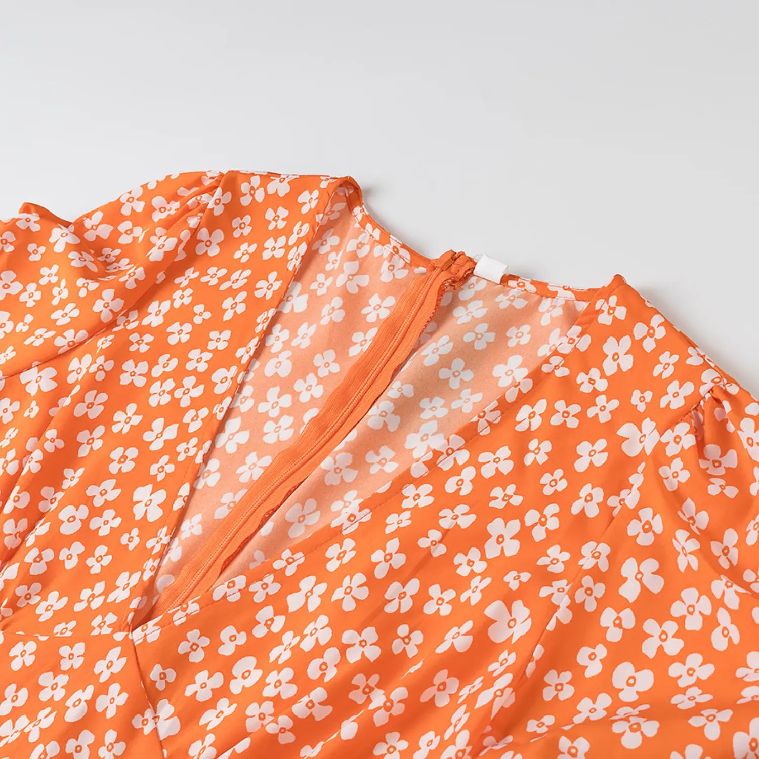 Close-up of the V-neckline and back zipper on the orange floral dress