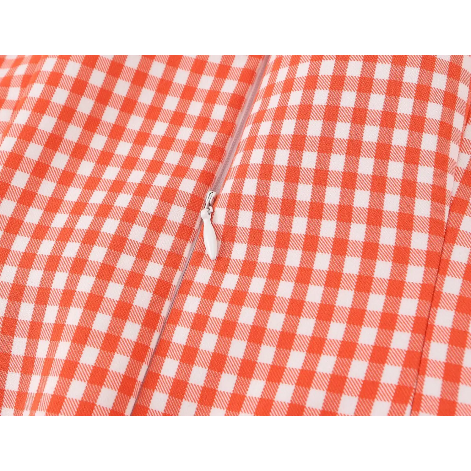 Close-up of white invisible zipper with elongated fabric pull tab, embedded vertical center back seam on gingham fabric