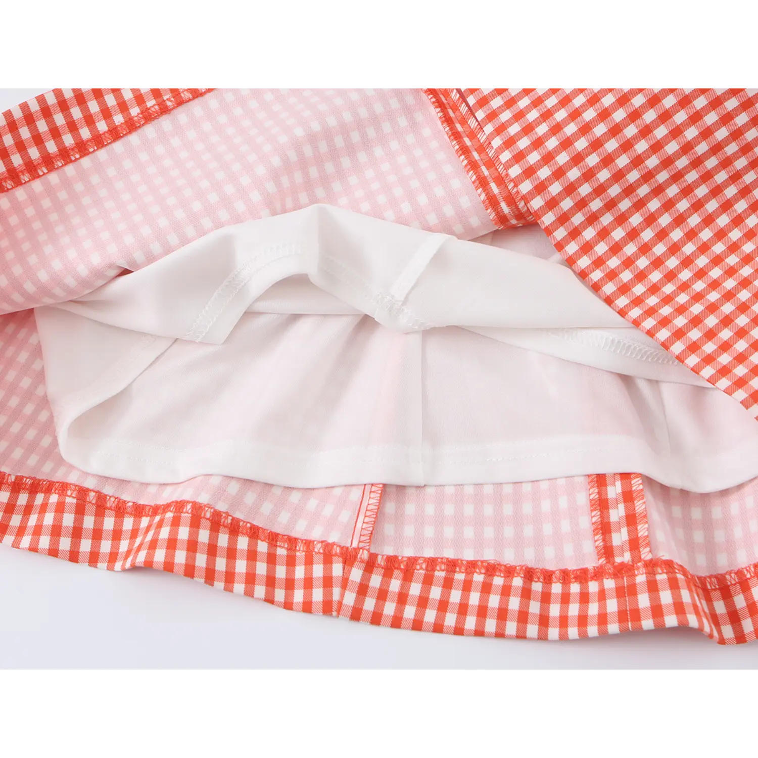Cross-section shot of skirt hem, outer gingham shell + full smooth white lining, finished serged edges for anti-fray