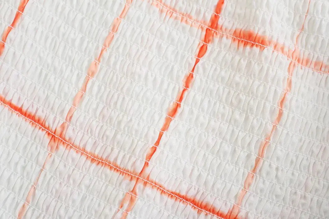Macro close-up of smocked bodice and orange grid print