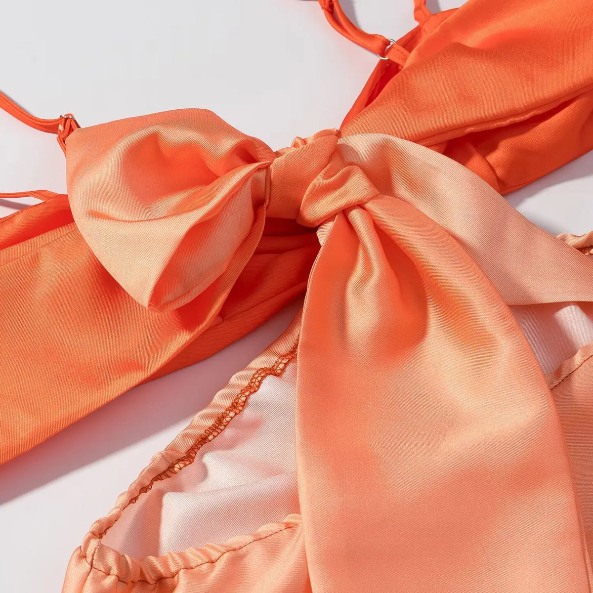 Close-up of large two-tone orange satin back bow on maxi dress, soft folded satin fabric with sheen