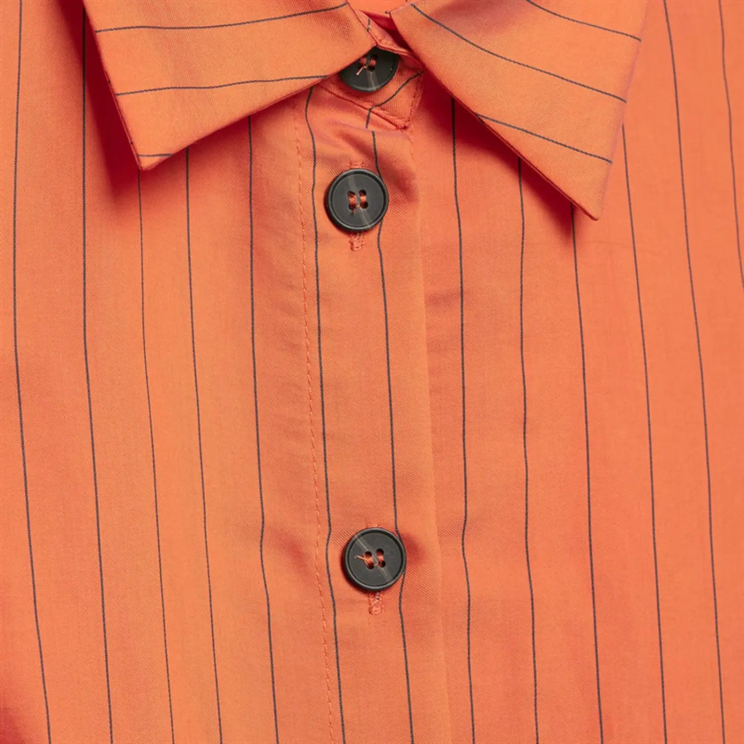 Extreme close-up of front placket, dark round buttons, buttonhole stitching, folded placket edge, vertical stripe alignment