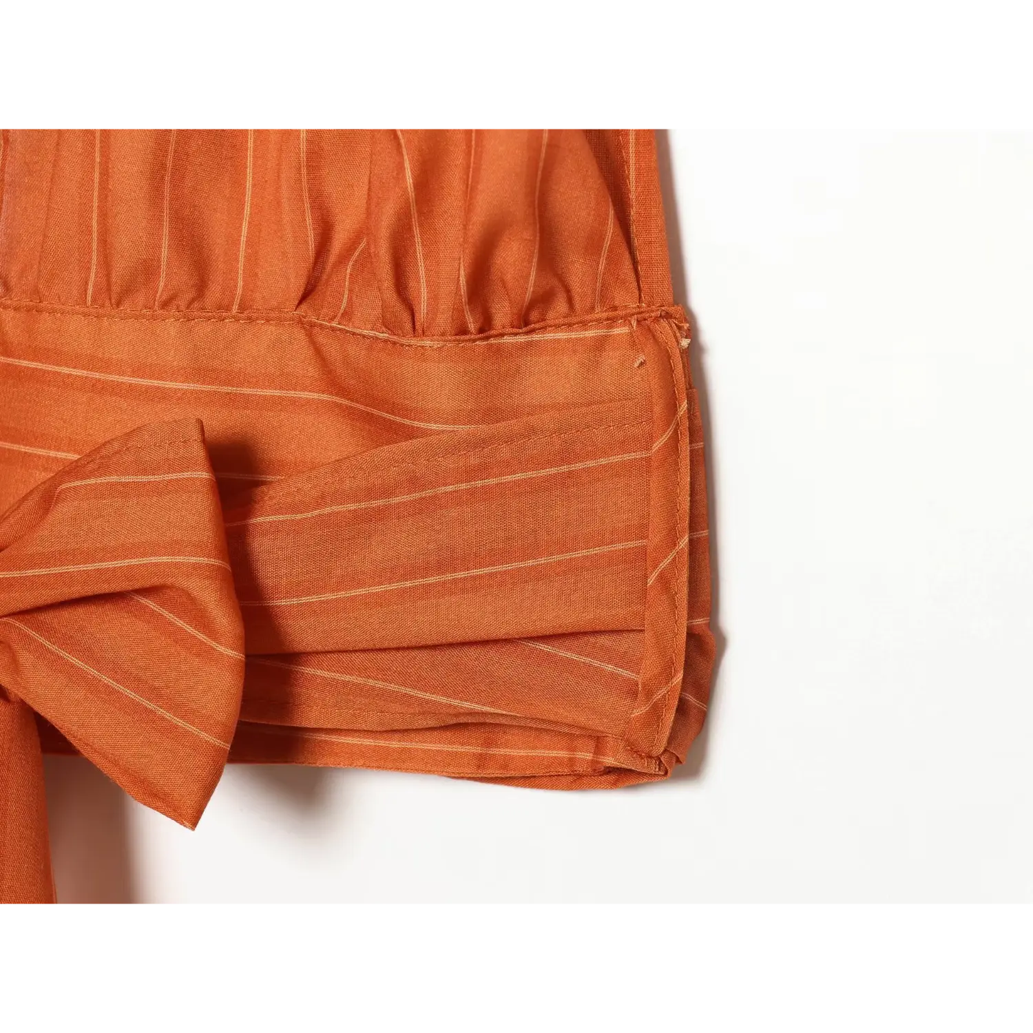 Close‑up hem and side seam workmanship of orange striped halter top waist band