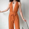 Female model wearing orange vertical stripe two‑piece coord set, deep v halter top and wide leg trousers