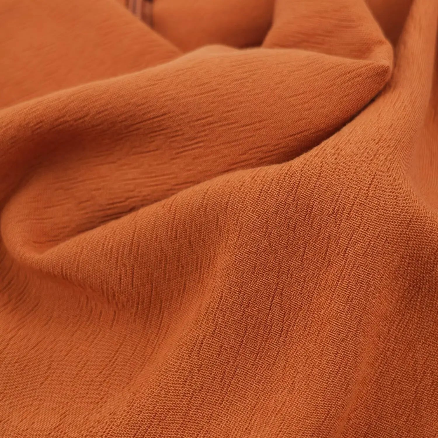 Draped fold close-up showing subtle vertical texture on rust romper fabric