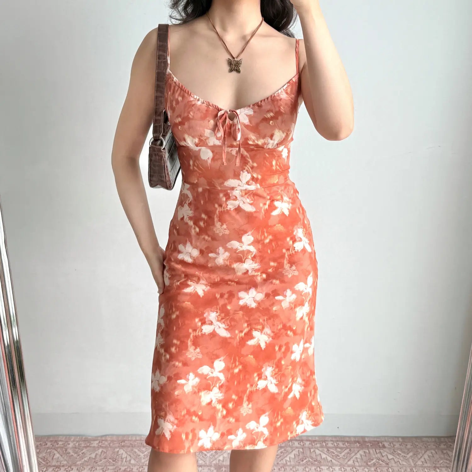 Mirror selfie of the orange floral slip dress, highlighting bust tie and slim bodycon fit