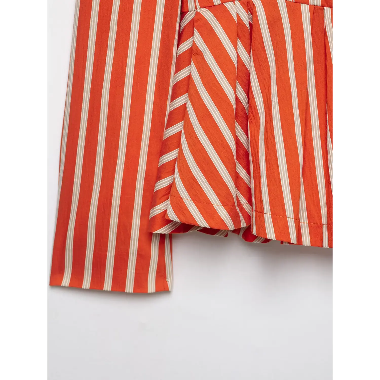 Close‑up peplum hem and sleeve cuff of orange white vertical stripe blazer