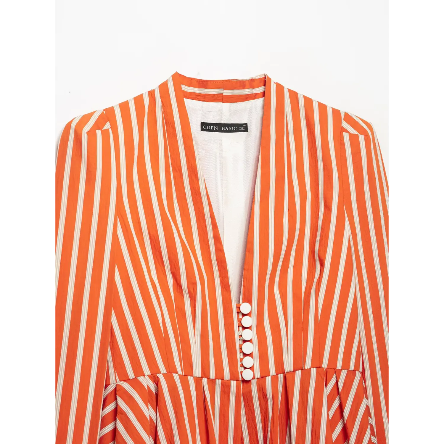 Close‑up v‑neck, front white buttons and inner brand label on orange striped blazer