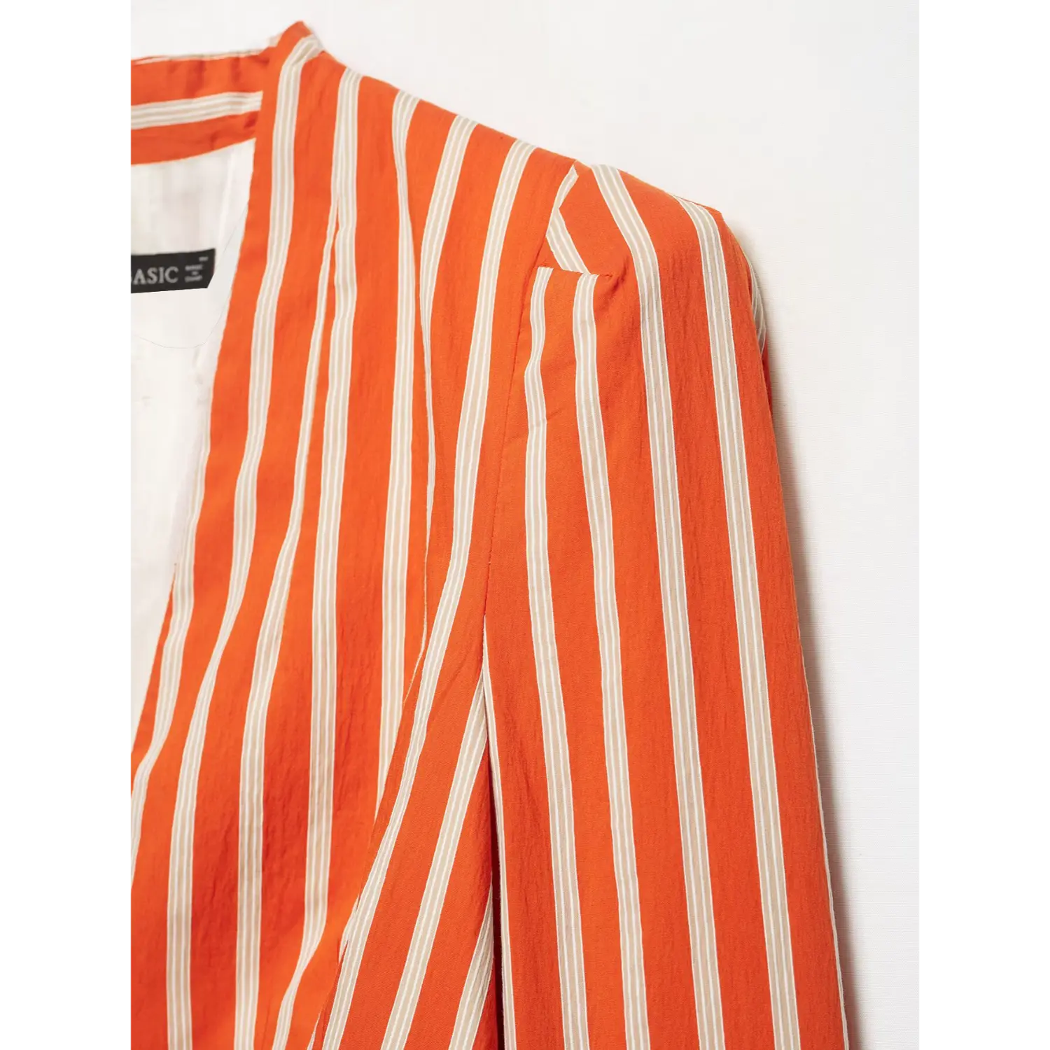 Shoulder and collar close‑up of orange white striped peplum blazer