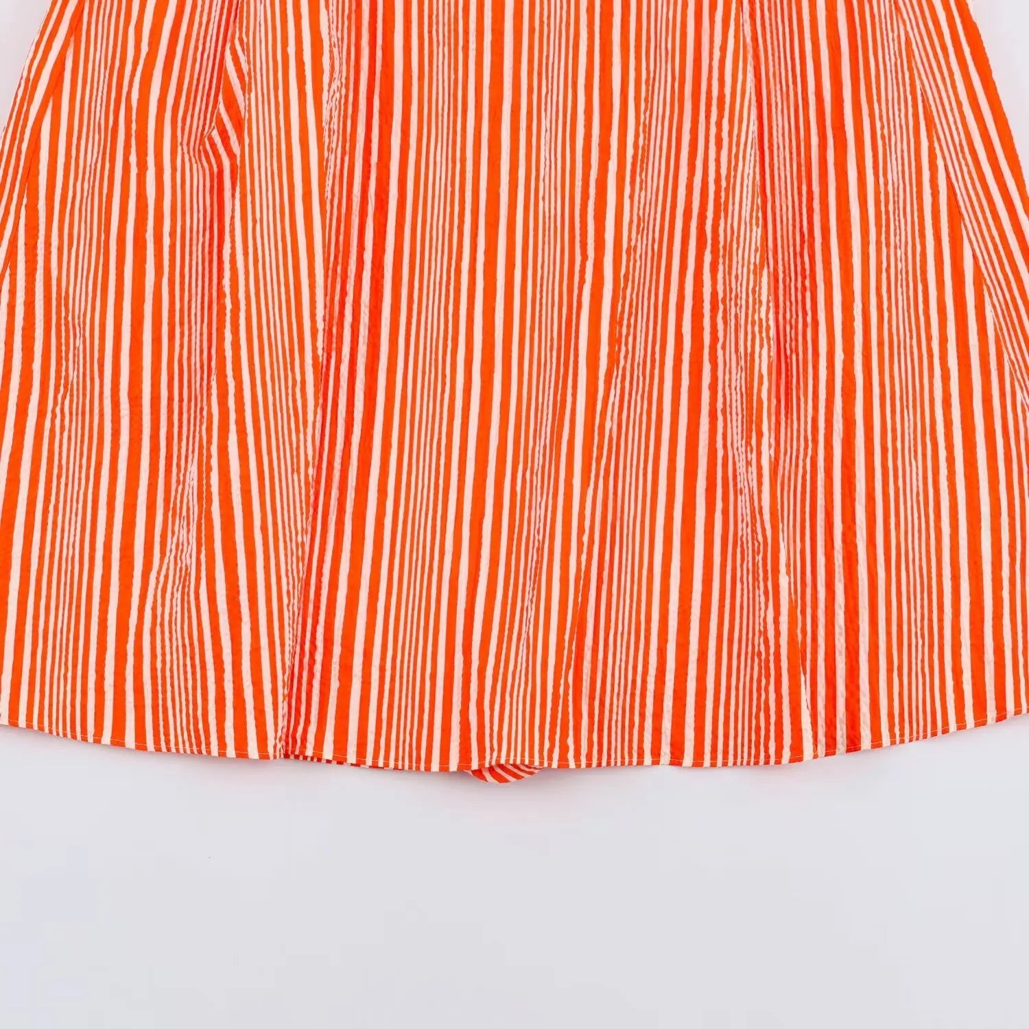Close‑up of orange white stripe flowy skirt hem fabric