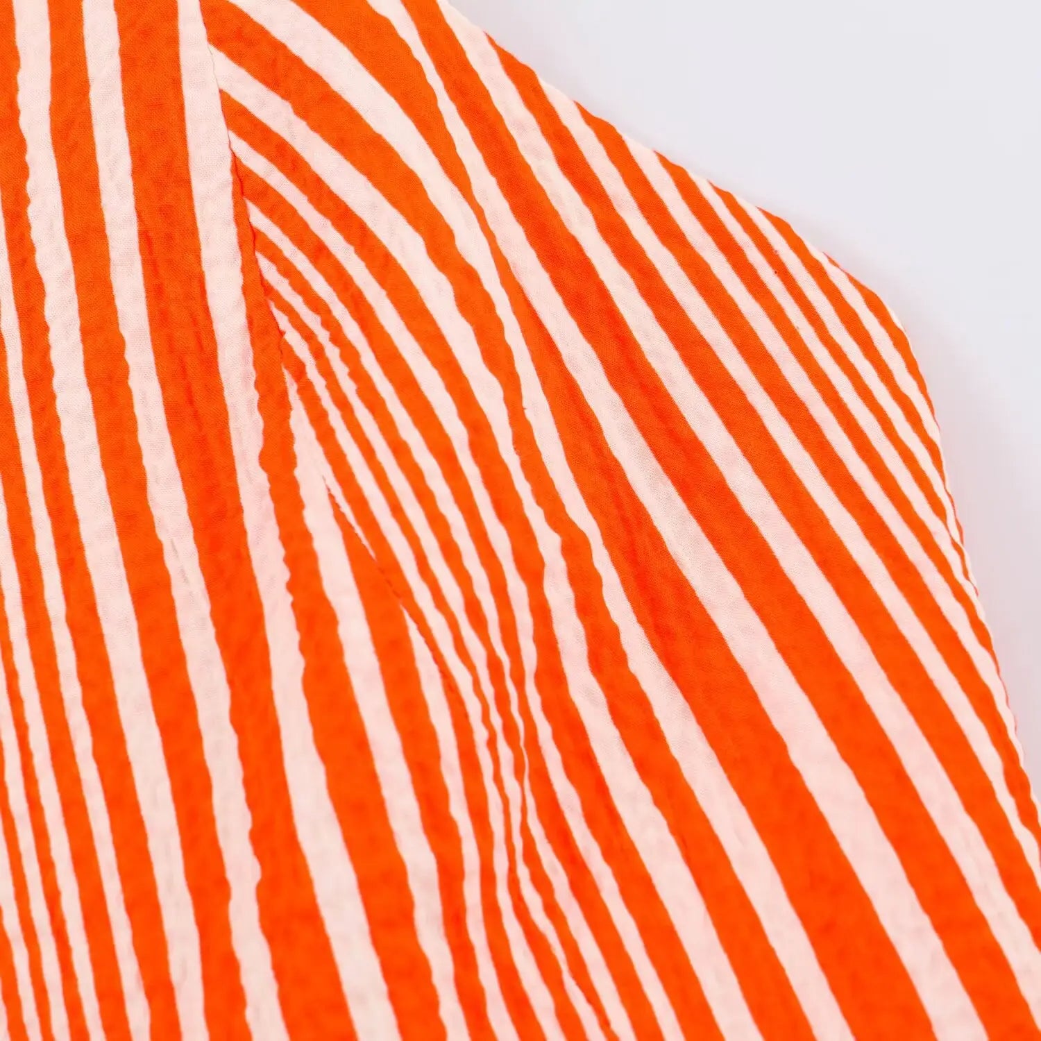 Detailed close‑up of lightweight orange white vertical stripe fabric