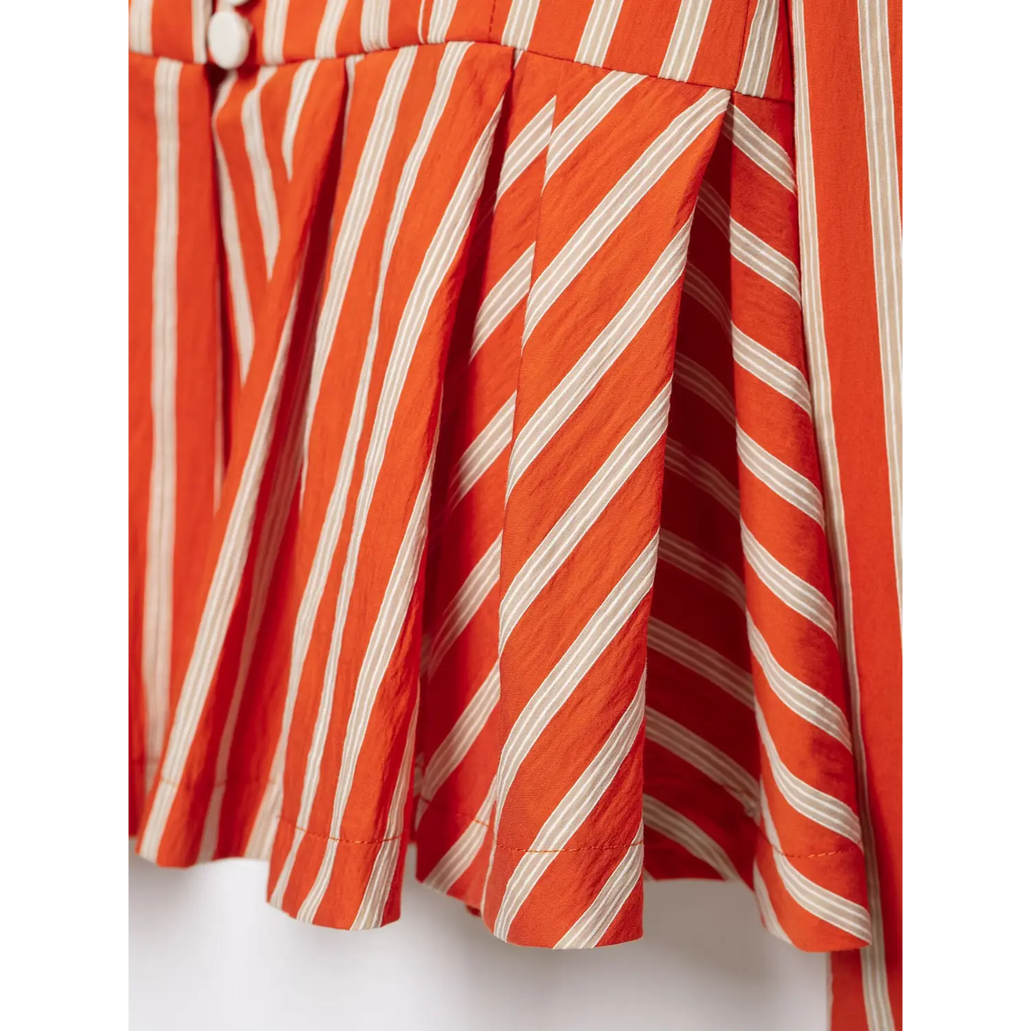 Close‑up hem detail of orange white striped peplum blazer