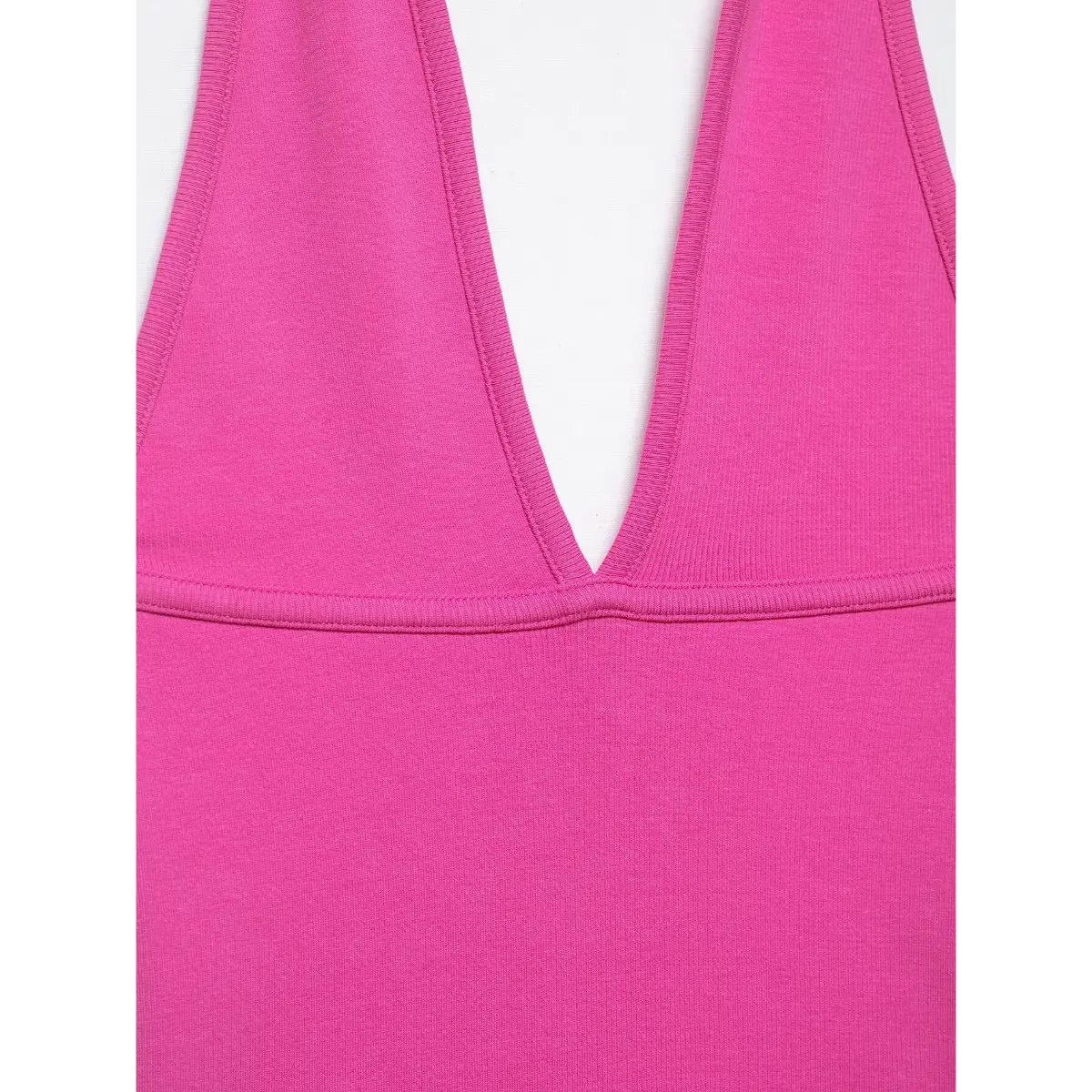 Close-up of the hot pink halter top, showing the deep V-neckline, ribbed fabric texture, and neat stitching details.