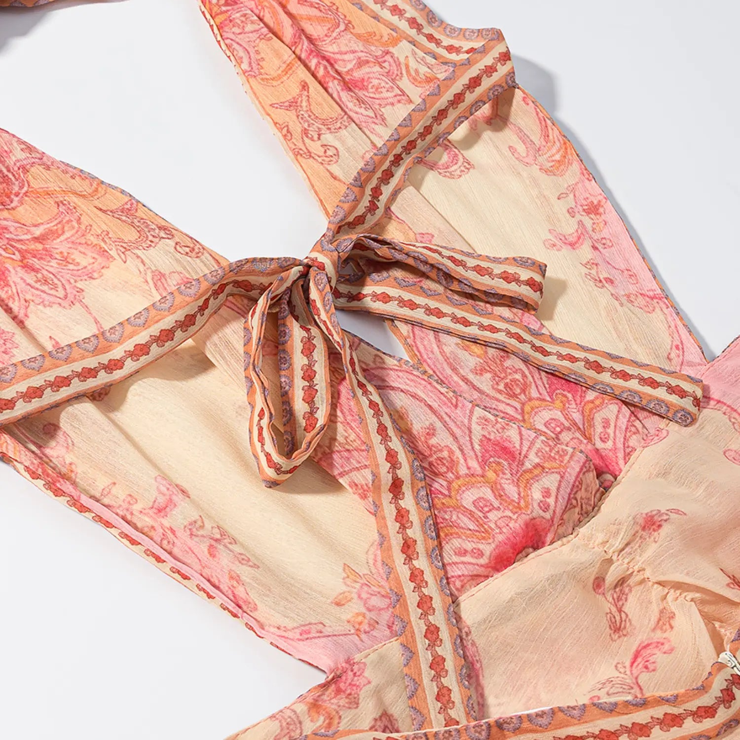 Waist partial close-up, front self fabric tie knot, border print trim, peach pink paisley sheer chiffon fabric