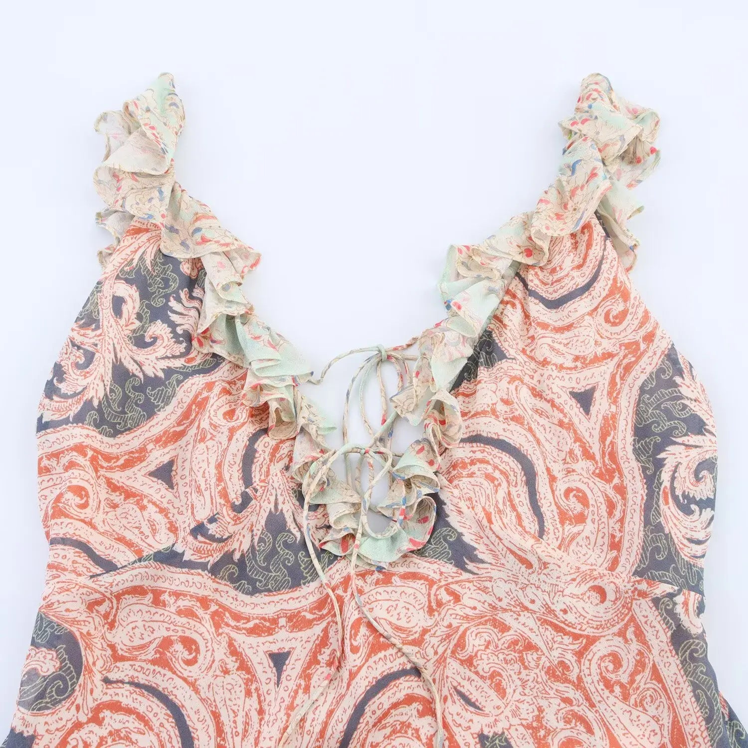 Close‑up of deep v‑neckline, frilled ruffle spaghetti straps, crisscross lace‑up tie detail, vintage paisley chiffon print