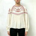 Model wearing cream paisley embroidered puff sleeve peplum blouse