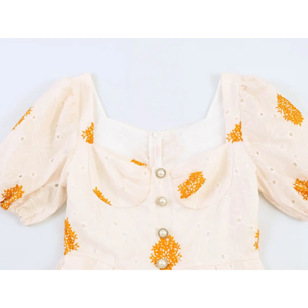 Close-up of square neckline and delicate pearl button decoration on printed maxi dress bodice