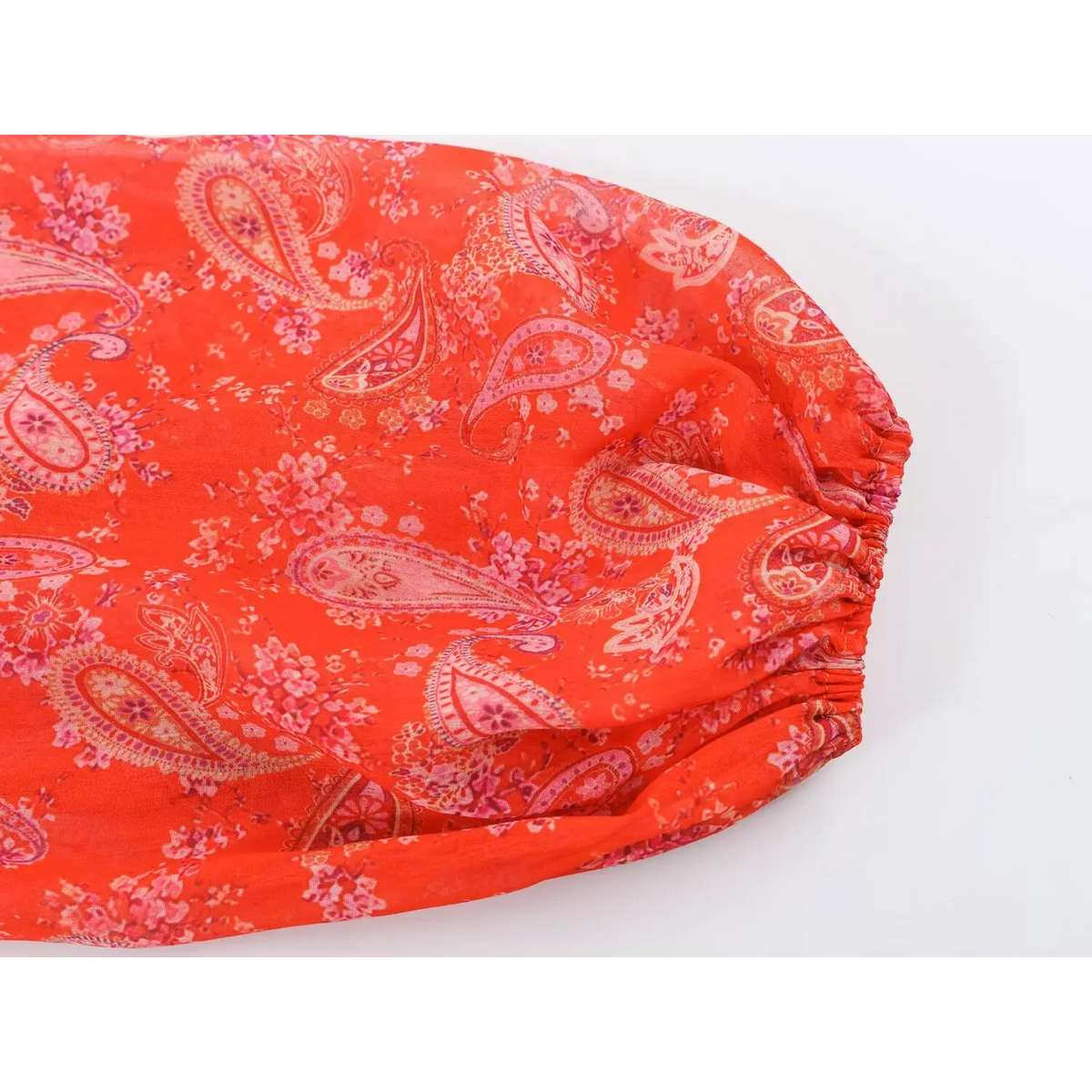 Close-up of balloon sleeve elastic cuff of paisley print maxi dress, red fabric with pink paisley floral print