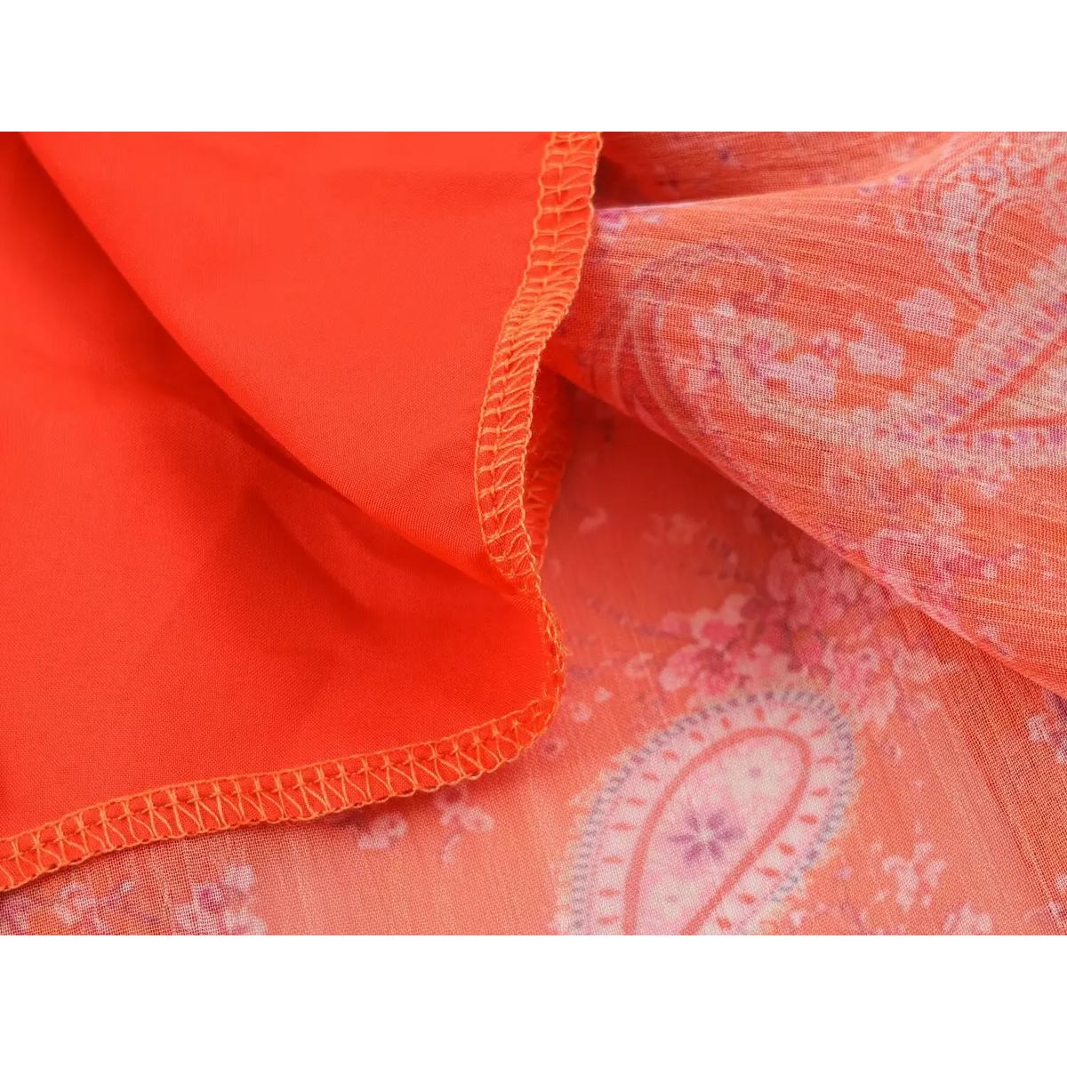 Close-up of dress hem overlock stitching, showing inner lining and semi-sheer printed outer fabric